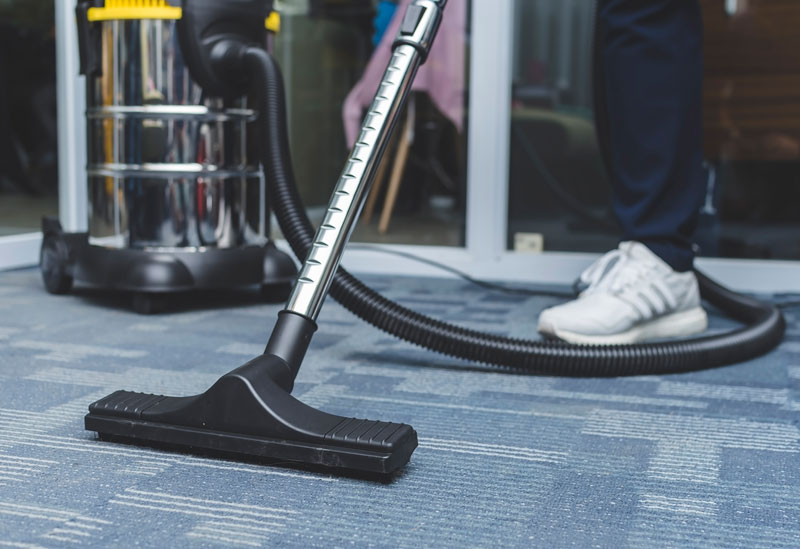Commercial-office-cleaning someone vacuuming the carpet in a office space