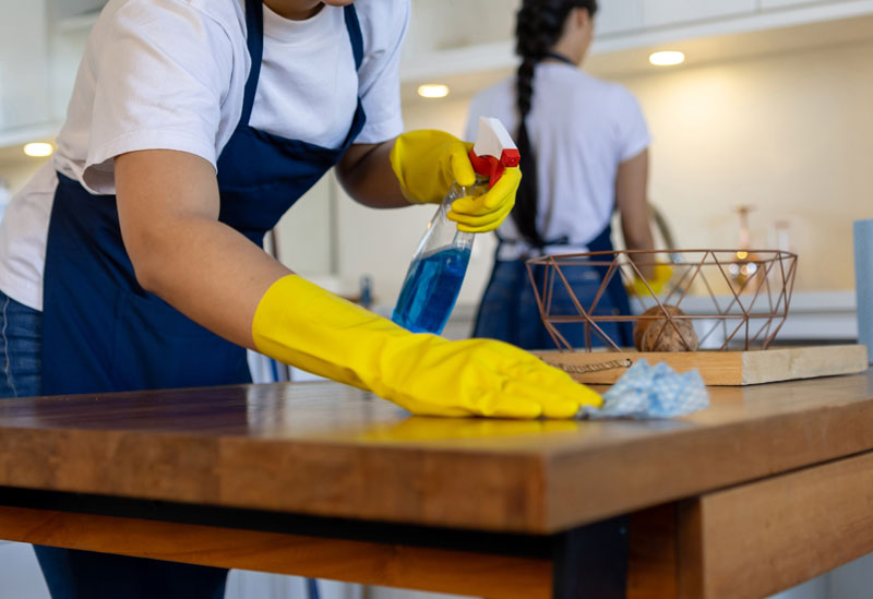 Residential-Cleaning-service women cleaning a wooden table in a home